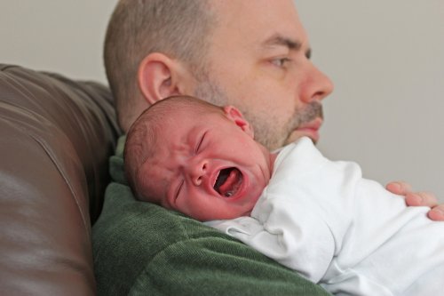 bebê chorando no colo do pai