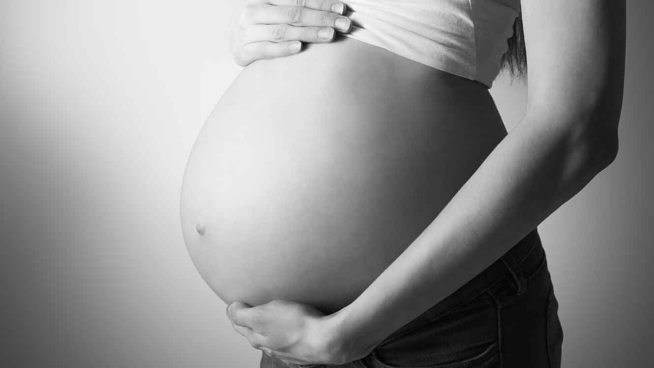 mulher grávida segurando sua barriga com as mãos
