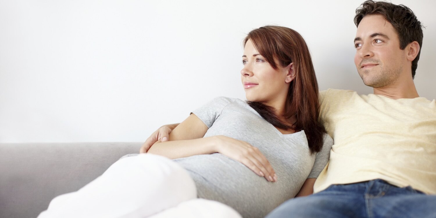 mulher grávida e parceiro juntos olhando para o mesmo lugar