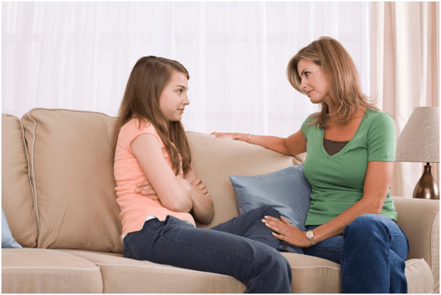 mãe e filha sentadas no sofá conversando