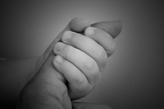 mão do bebê segurando o dedo da mãe 