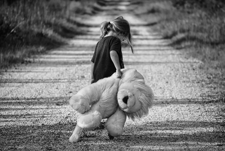 menina andando sozinha em uma estrada carregando um bicho de pelúcia