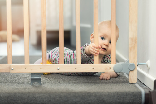 bebê segurando as grades de proteção da escada