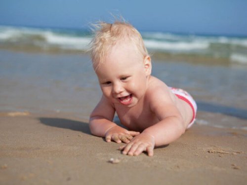 bebê engatinhando sobre a areia da praia