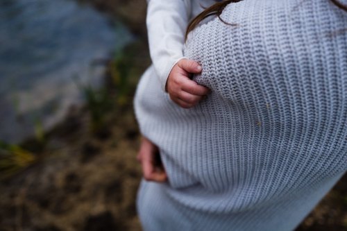 Bebê no colo da mãe segurando sua blusa