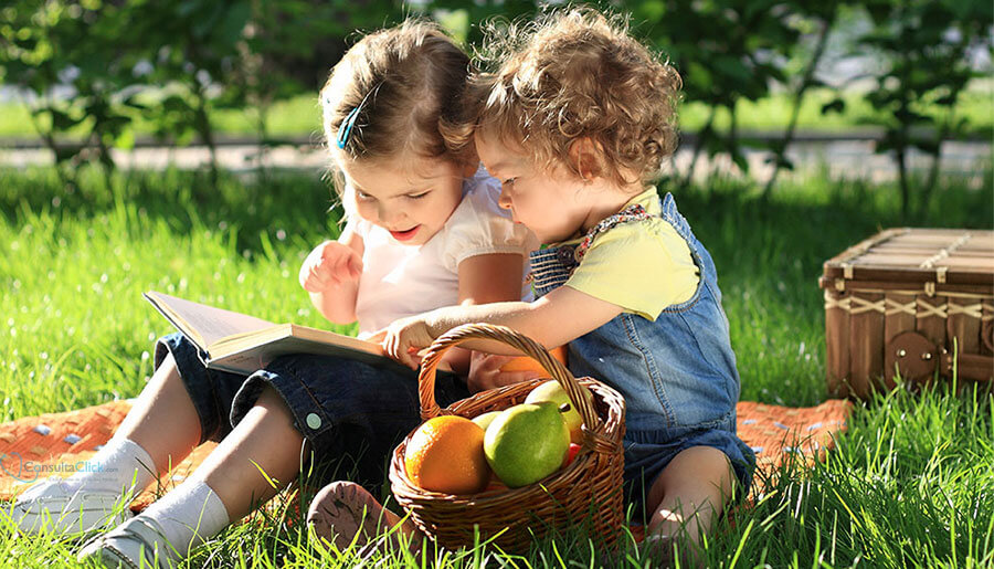 duas crianças sentadas na grama lendo um livro
