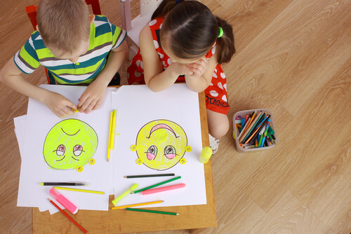 menino desenhando uma carinha triste e menina desenhando uma carinha feliz