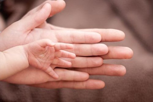 três mãos juntas, do pai, da mãe e do bebê