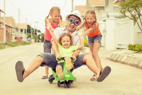 pai brincando de carrinho com seus filhos