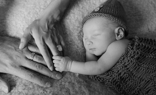 bebê segurando o dedo da mão dos padrinhos