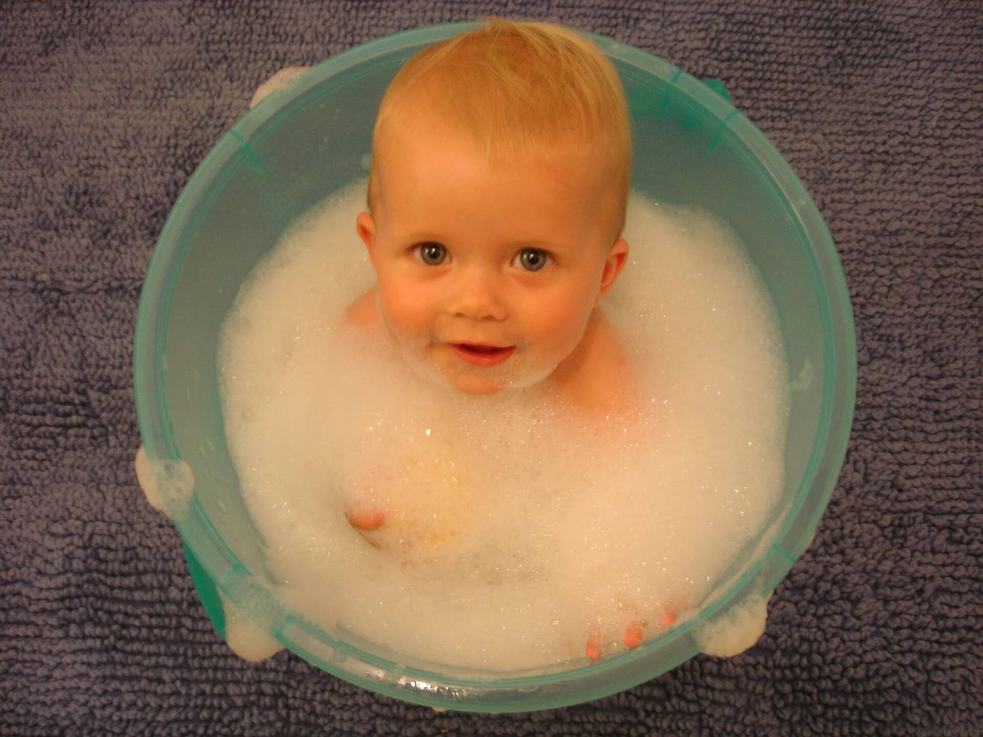 bebê tomando banho em uma bacia de espuma