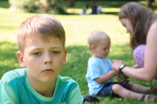 mãe dando atenção ao filho mais novo, irmão mais velho com ciúmes