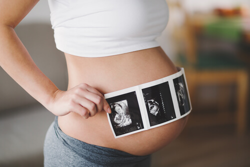 Mulher grávida com fotos de ultrassom sobre a barriga