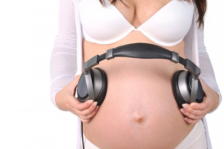 mulher grávida com fone de ouvido na barriga