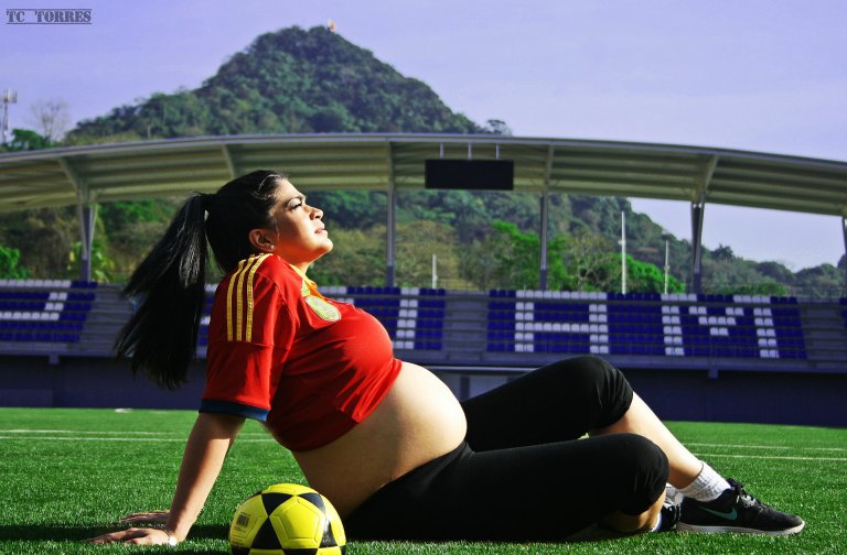 mulher grávida sentada em um campo de futebol