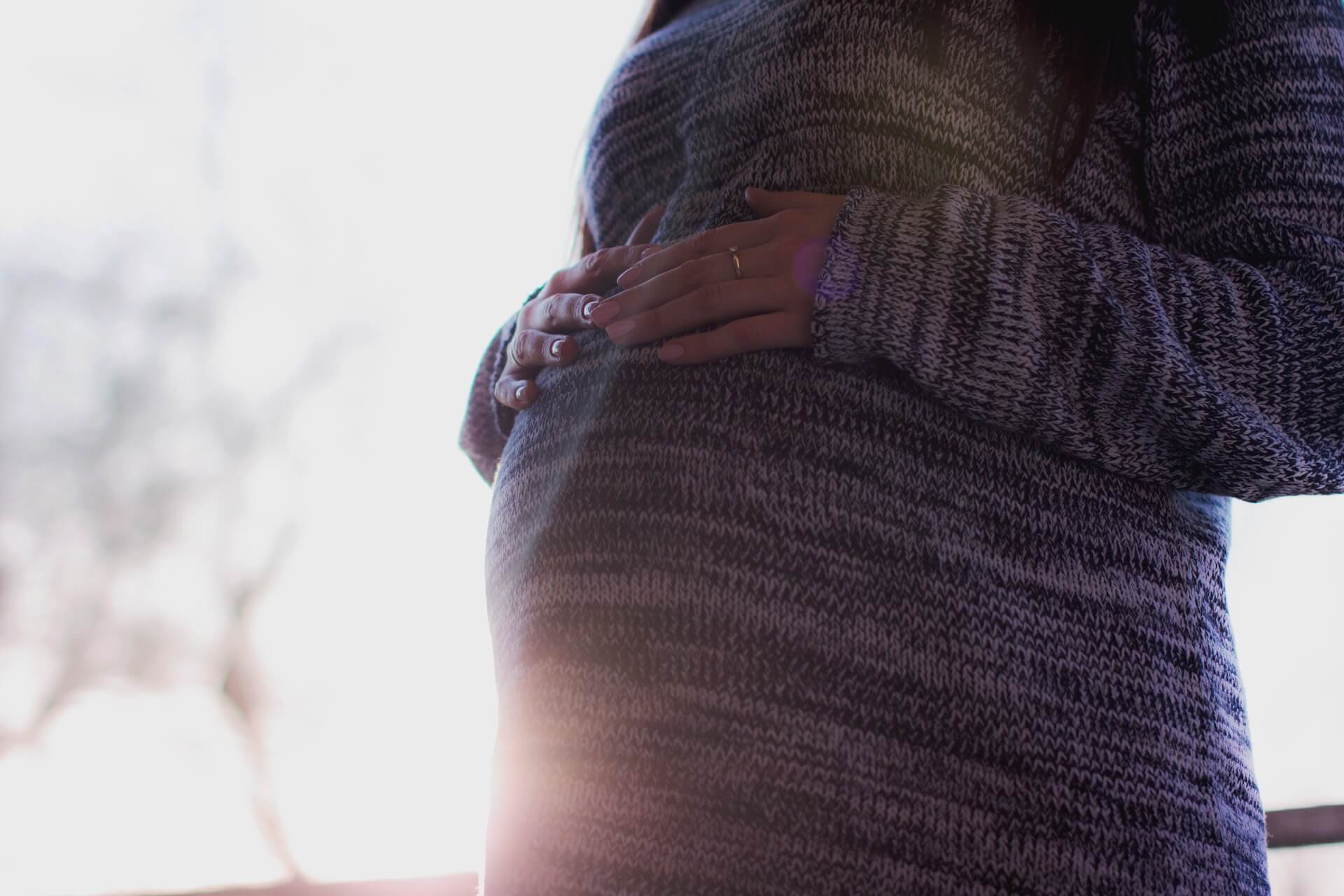 mãe grávida com as mãos sobre a barriga da segunda gravidez 