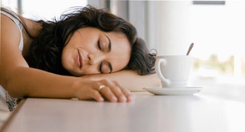 mulher dormindo com uma xícara de café na sua frente, método japonês contra a preguiça