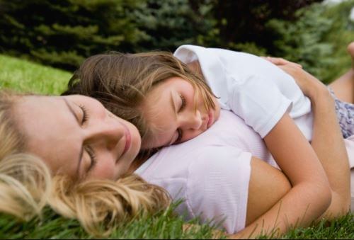 Mãe deitada na grama com filha