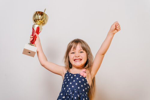 menina segurando um troféu, castigos e recompensas