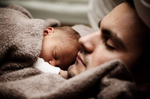 Pai dormindo com o filho para fazer o bebê dormir