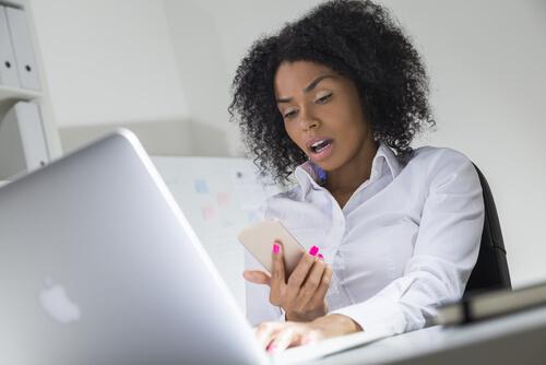 mulher olhando para o celular espantada