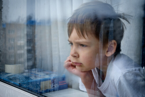 criança olhando atraves da janela em dia de chuva