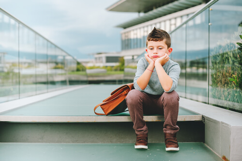 menino triste com a mochila escolar
