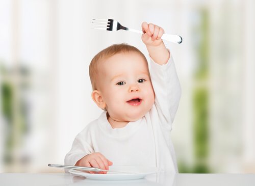 bebê feliz segurando garfo