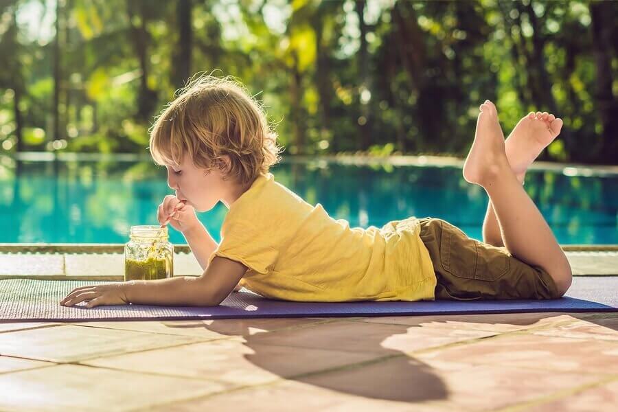 criança tomando um shake de frutas na piscina no verão