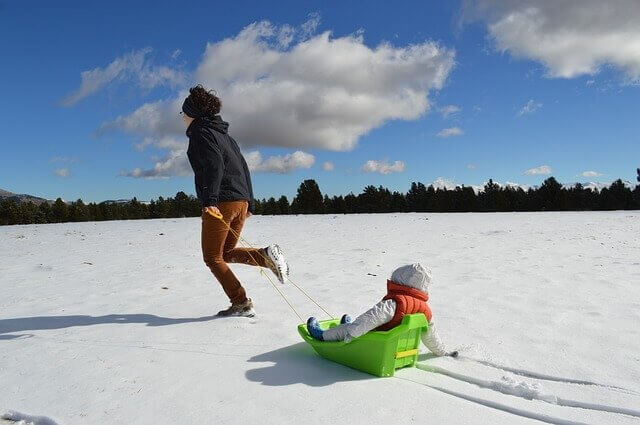 mãe e filha brincando com trenó na neve