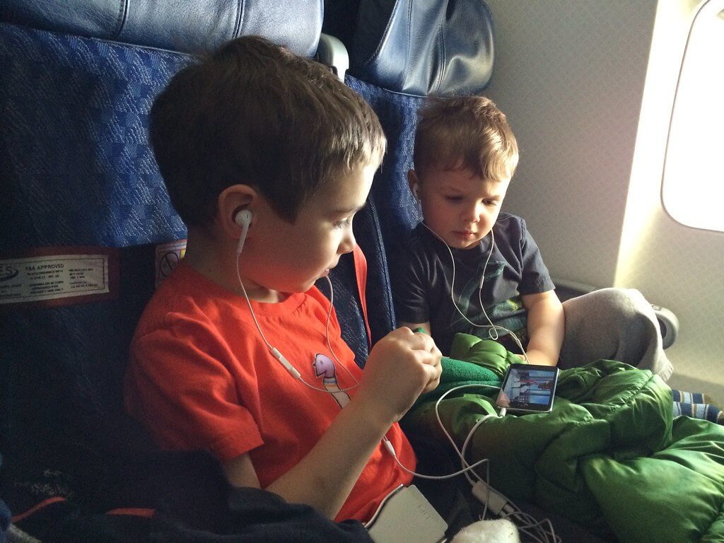 Meninos assistindo no celular dentro do avião.