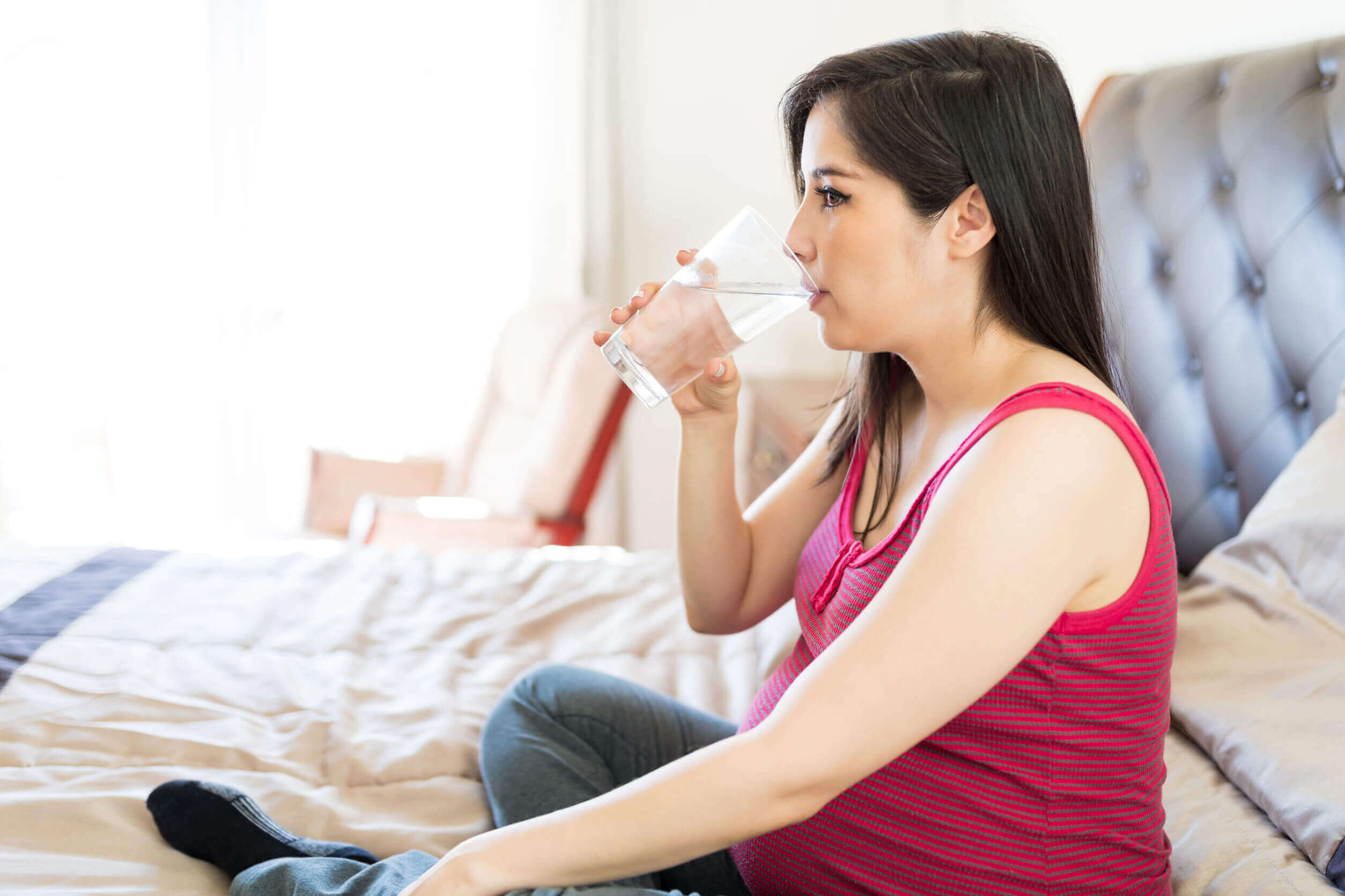 Mulher bebendo água durante a gravidez.