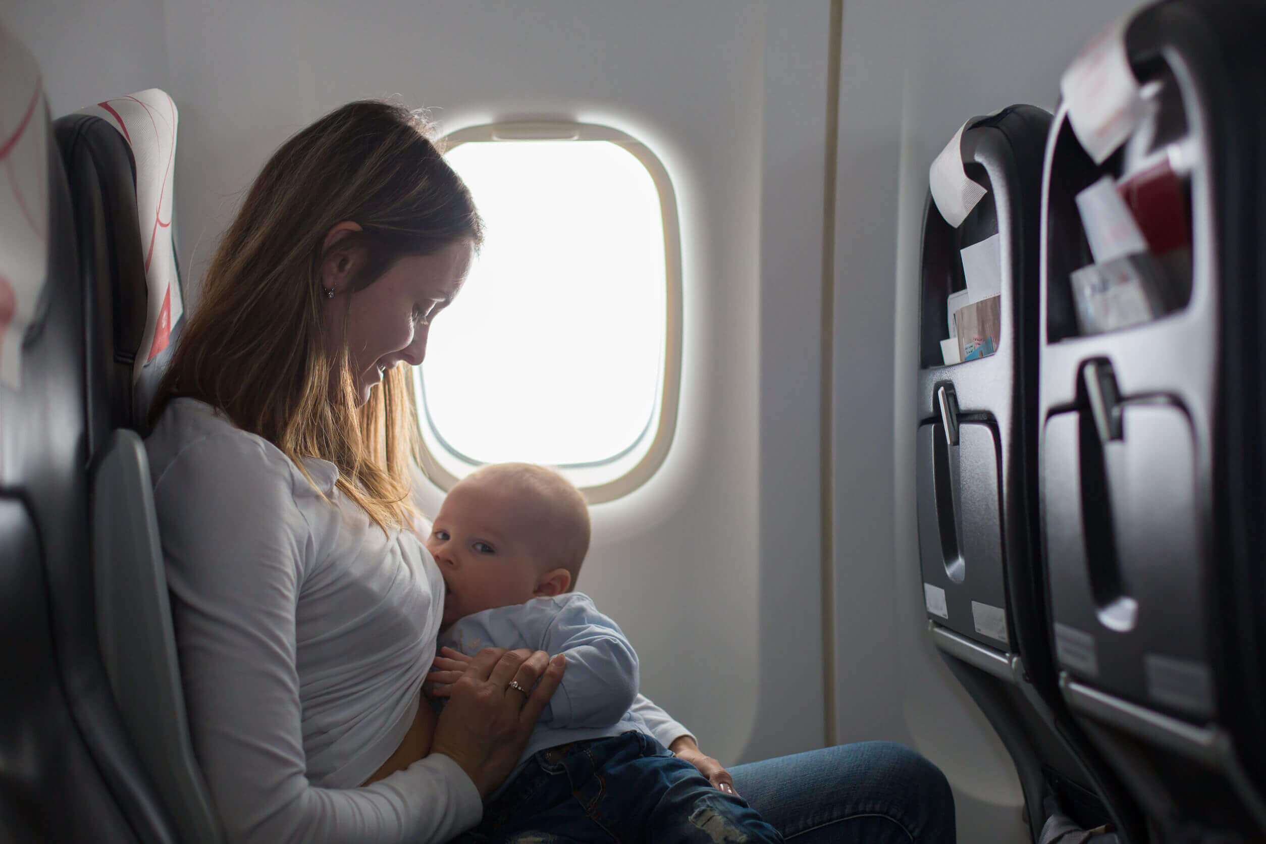 Mulher amamenta seu filho em um avião.