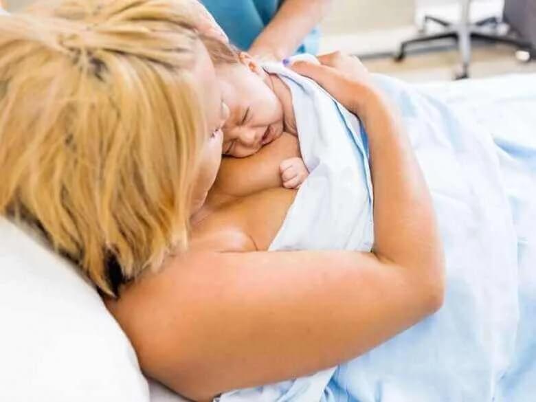 Mãe recebendo seu bebê no colo.