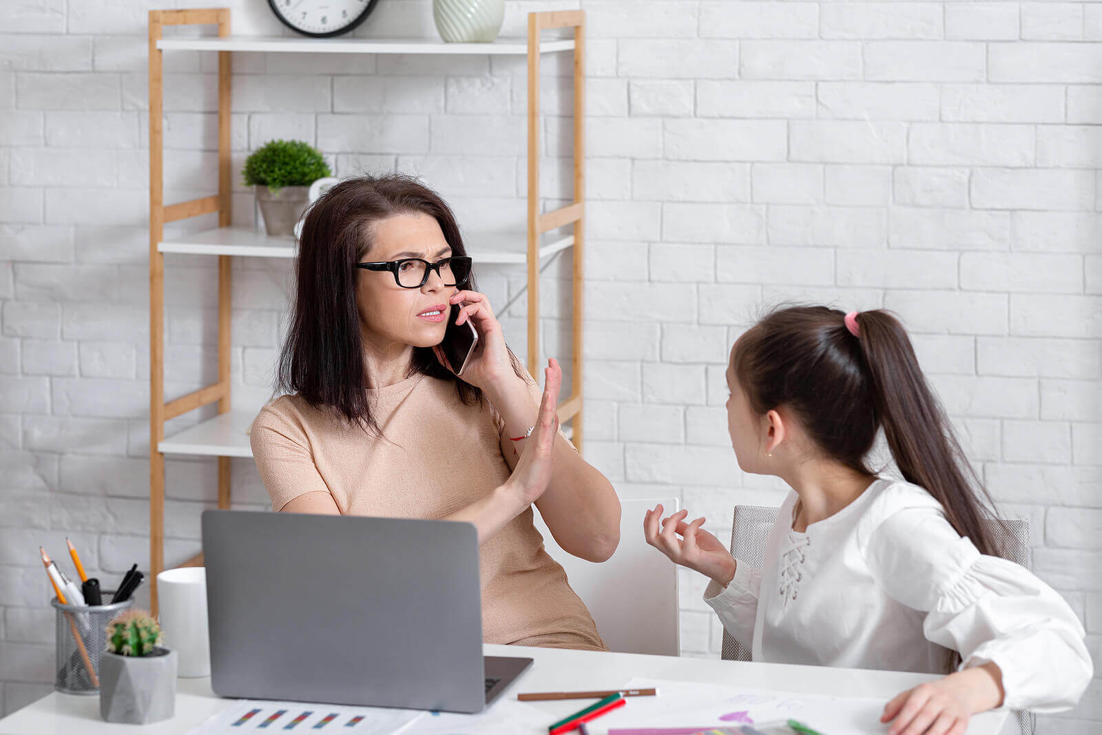 Mãe trabalhando enquanto faz a filha esperar porque ela não quer aprender a delegar.