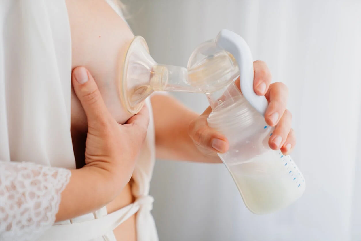 Mãe usando uma bomba tira-leite manual.