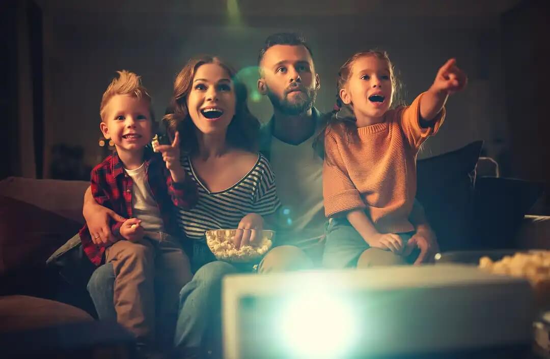 Família assistindo a um filme para criar momentos felizes.