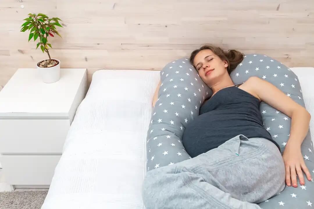Mulher deitada com um travesseiro para gravidez em forma de U