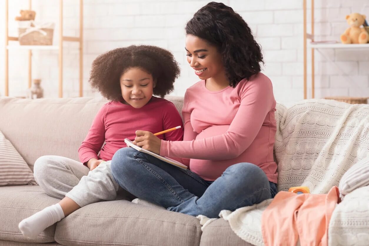 Mãe e filha fazendo uma lista de nomes de meninas que começam com a letra A.