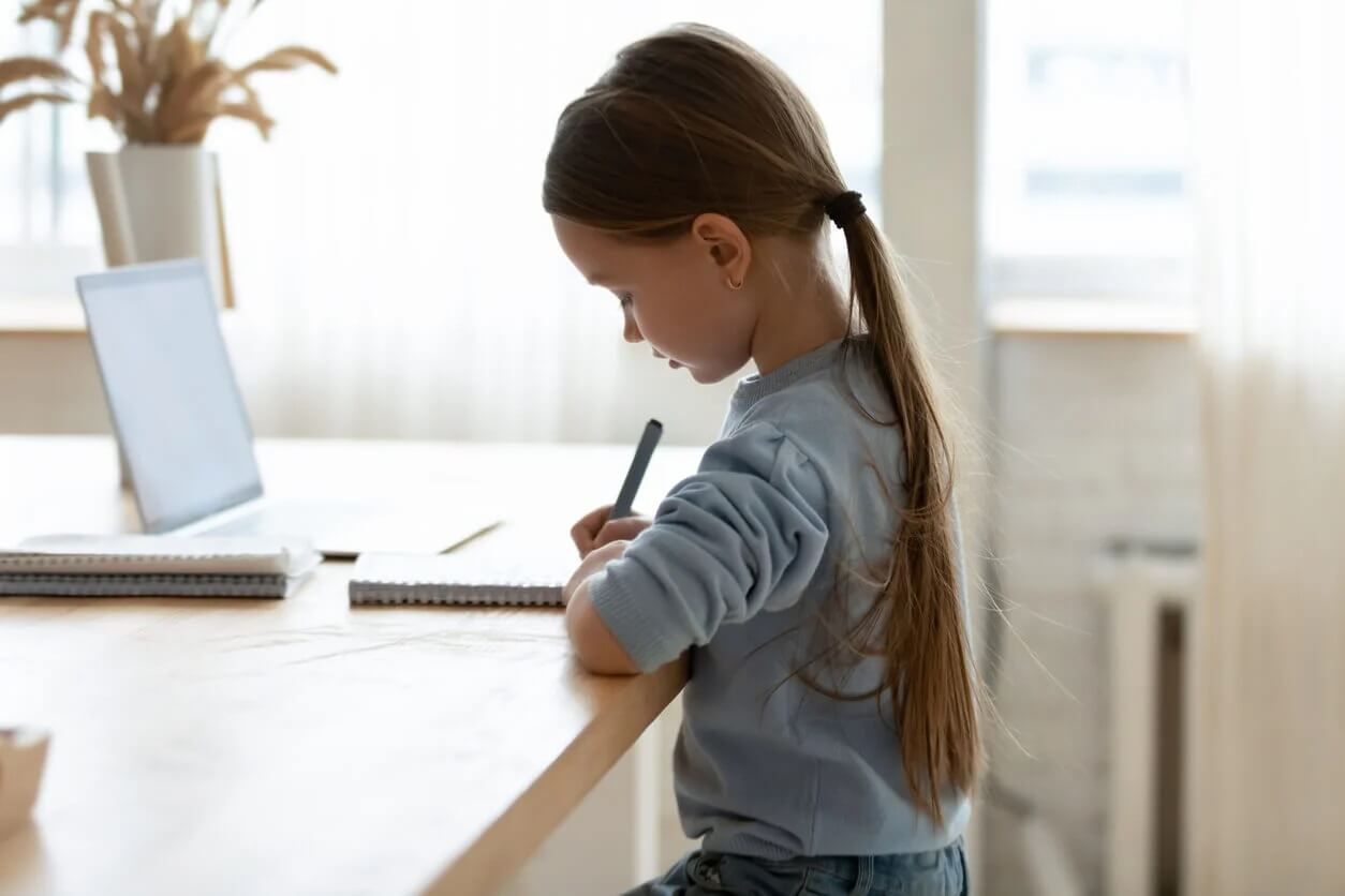 Menina fazendo lição de casa com boa higiene postural.