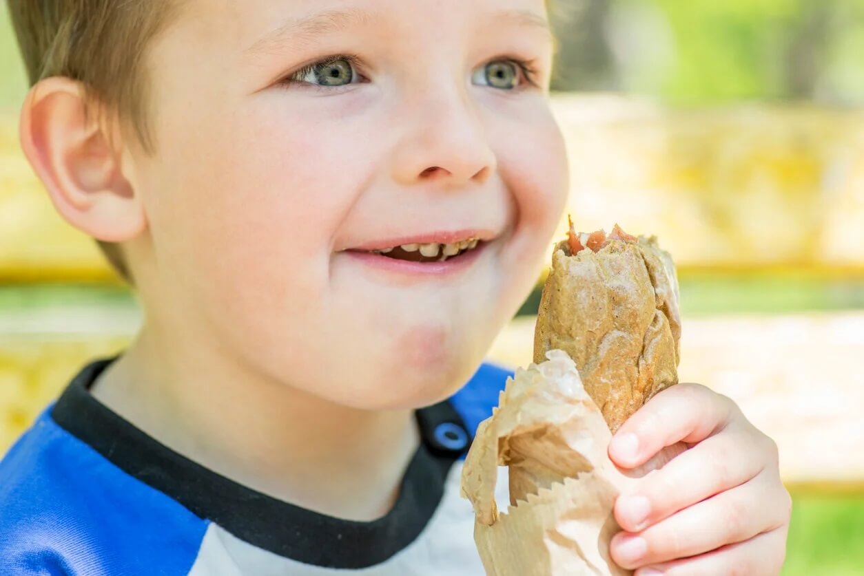 Criança comendo um sanduíche com pão integral.