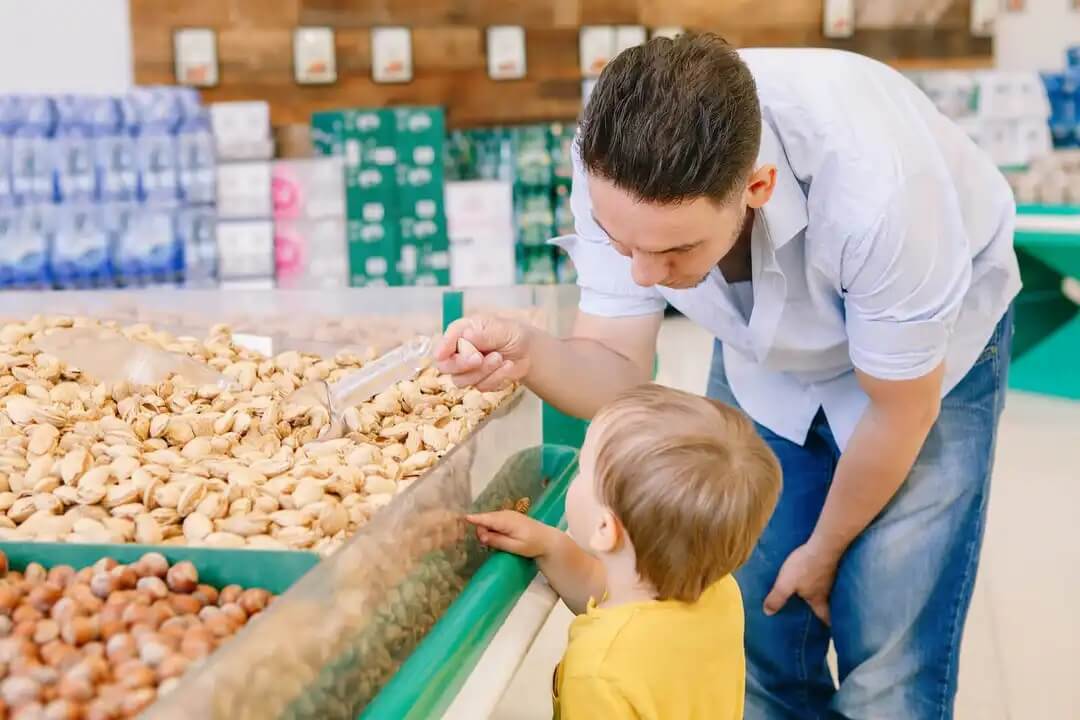 Pai com filho comprando nozes a granel.