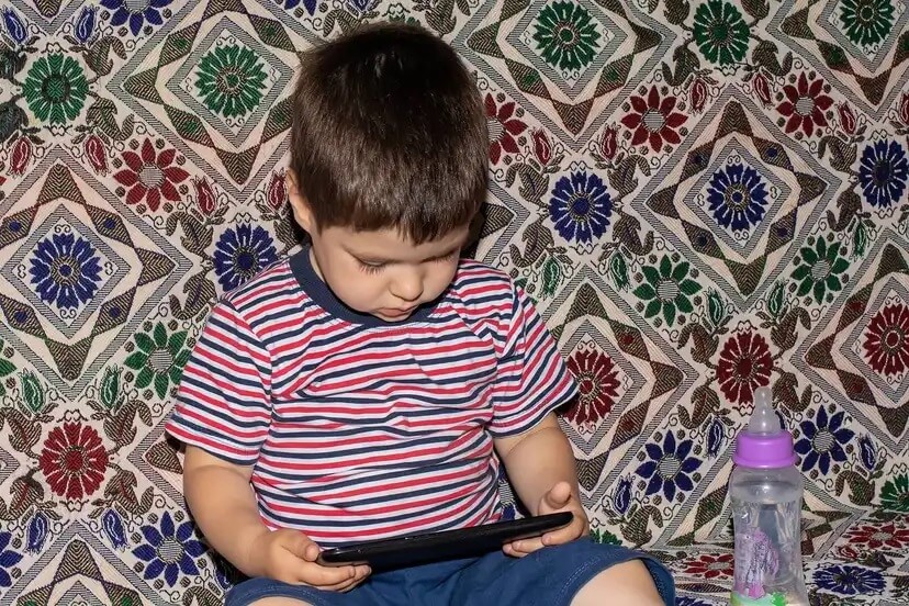 Criança assistindo filmes no tablet porque não consegue se desconectar das telas.