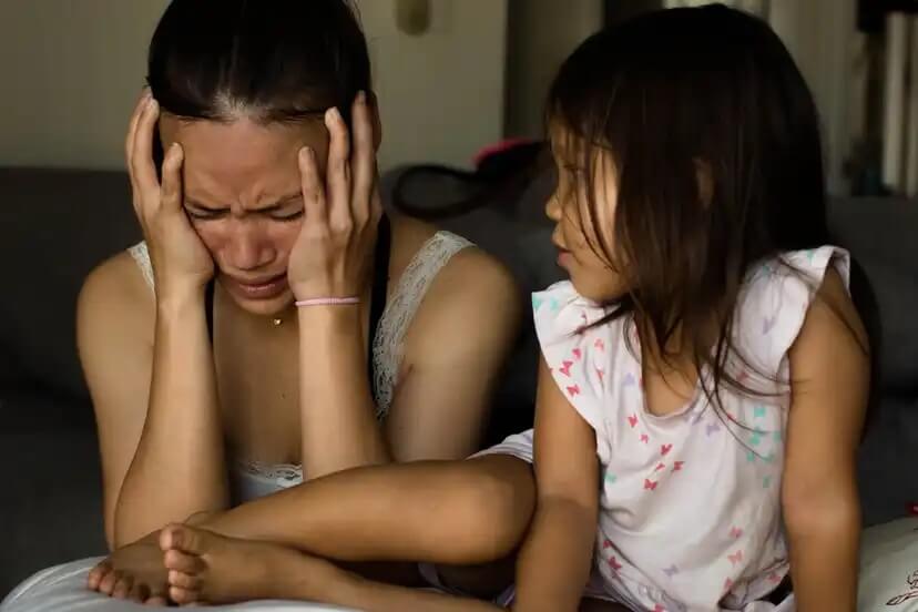 Mãe chorando na frente da filha porque sofre de depressão.