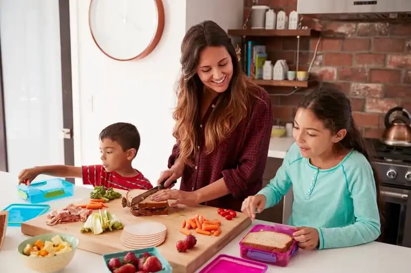 Mãe com seus filhos na cozinha preparando pratos saudáveis com todos os nutrientes necessários.