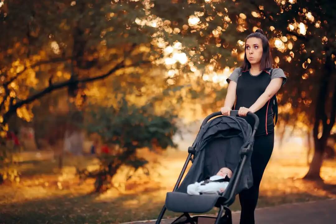 Mulher caminhando com seu bebê como parte da prática de exercício após o parto para se recuperar.
