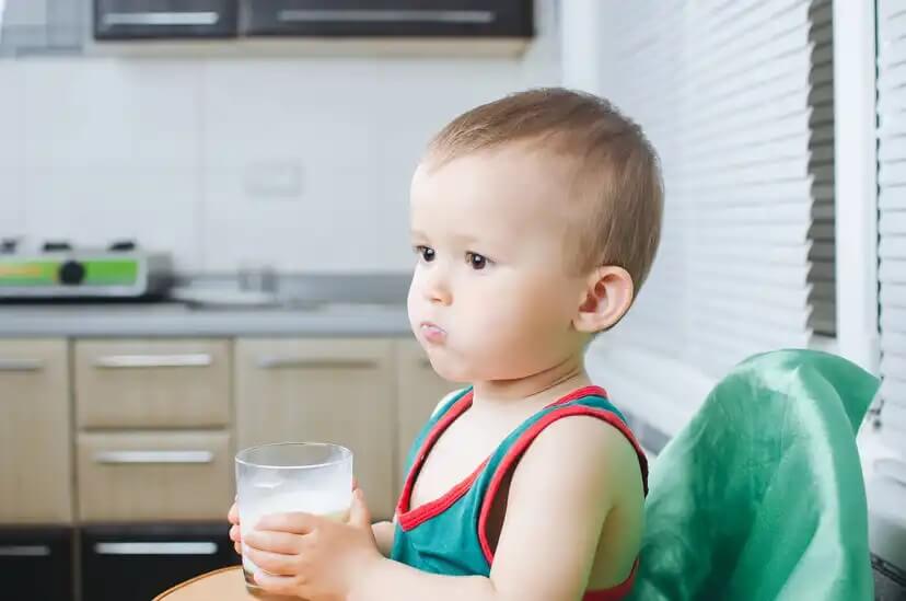 Criança bebendo um copo de leite.