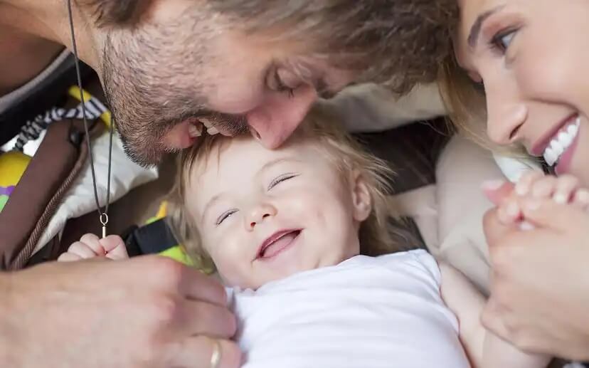 Pais brincando com seu bebê e fazendo-o rir para promover um apego seguro.