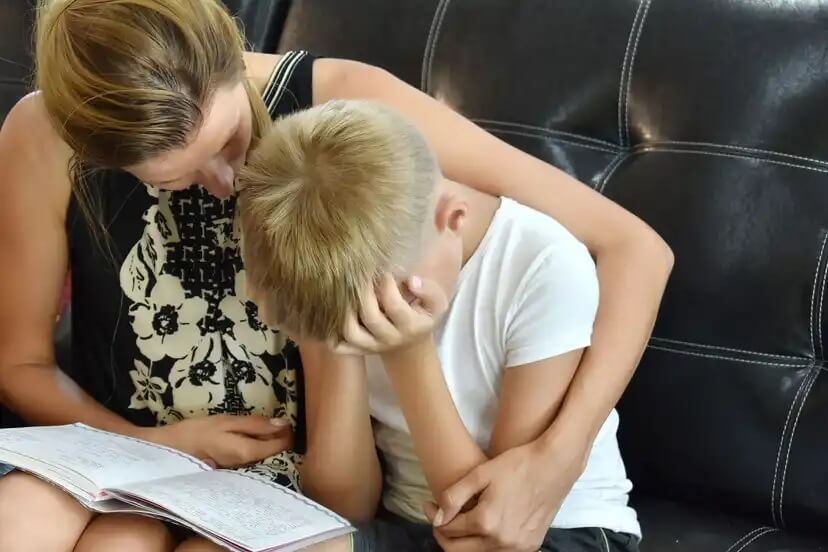 Mãe confortando seu filho enquanto lhe dá um abraço.