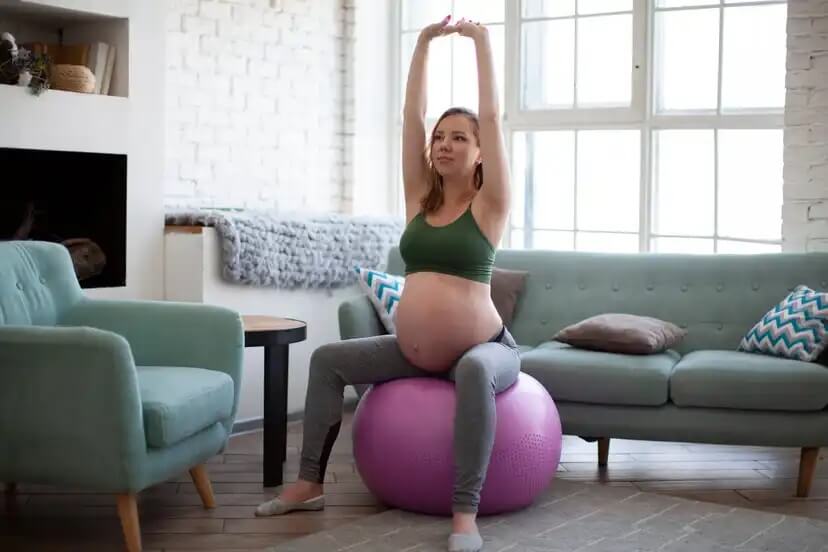 Mulher fazendo exercícios na bola medicial durante a gravidez.
